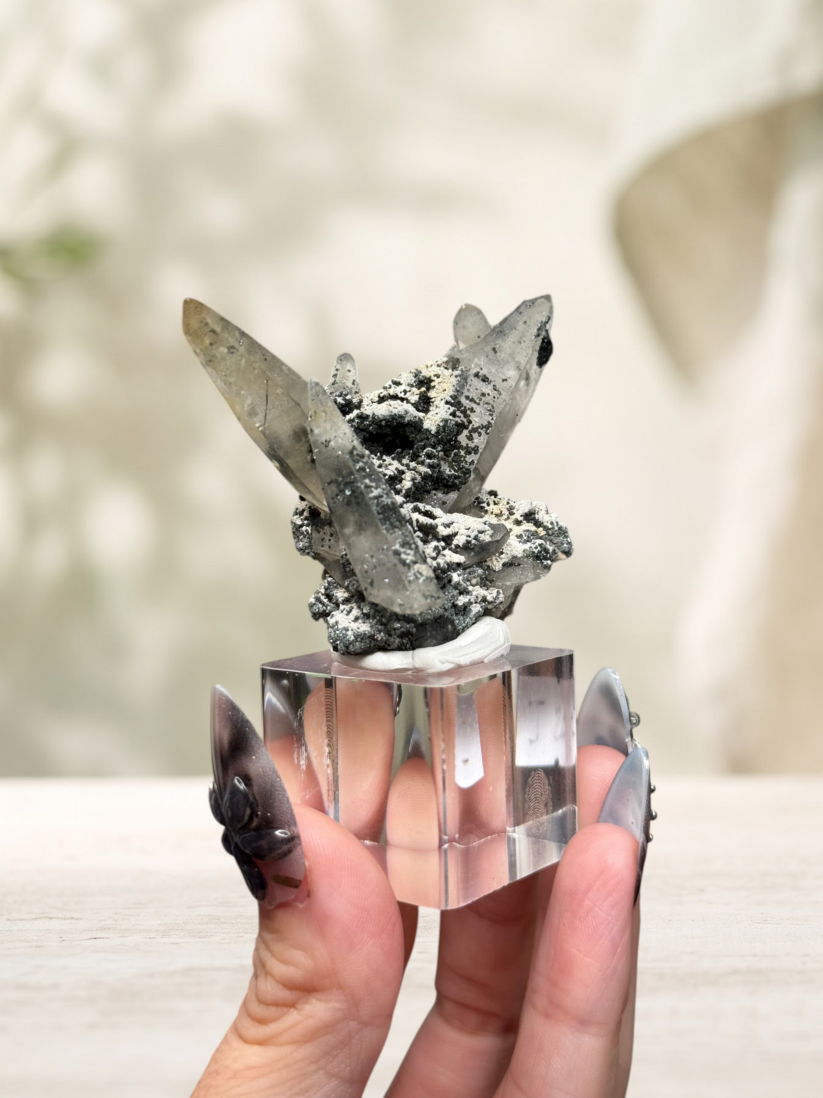 Crystal Glade laser quartz specimen from Pakistan with long tapering crystals and dark mineral inclusions on a stand