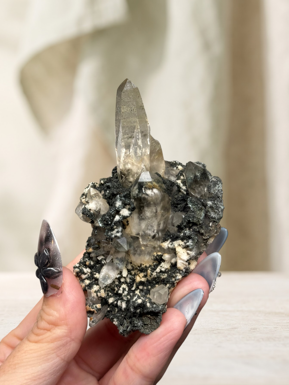 Crystal Glade laser quartz specimen from Pakistan featuring a slender, tapering clear crystal on a dark mineral matrix.