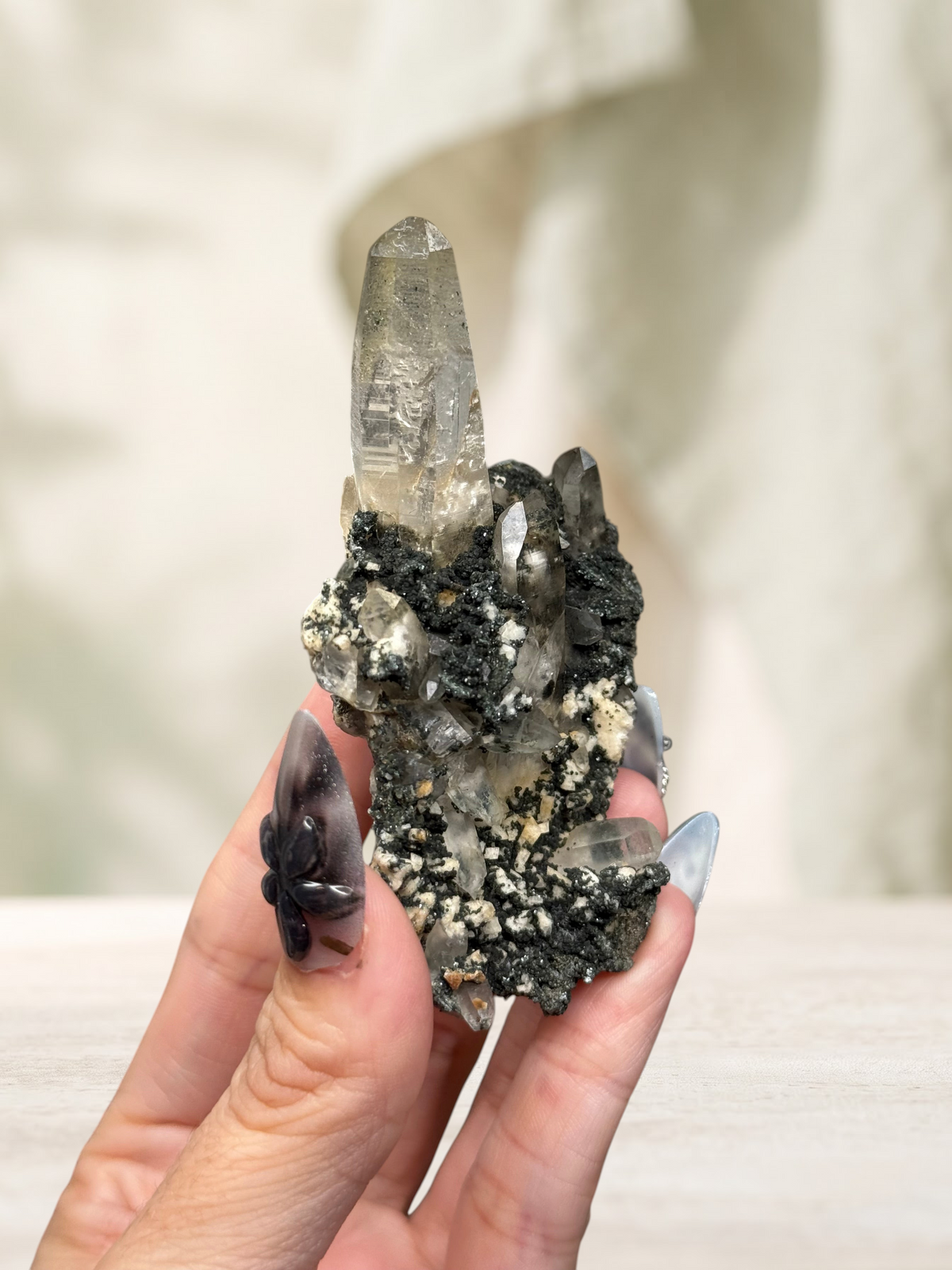 Crystal Glade laser quartz specimen from Pakistan featuring a slender, tapering clear crystal on a dark mineral matrix.