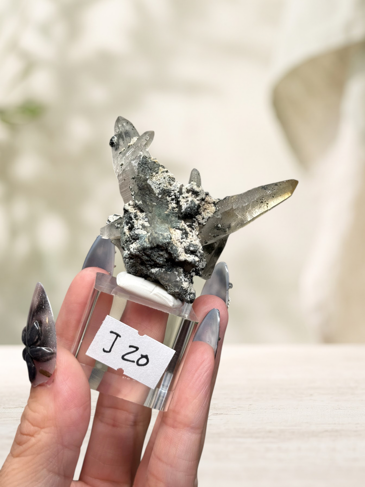 Crystal Glade laser quartz specimen from Pakistan with long tapering points and dark mineral matrix on a display stand